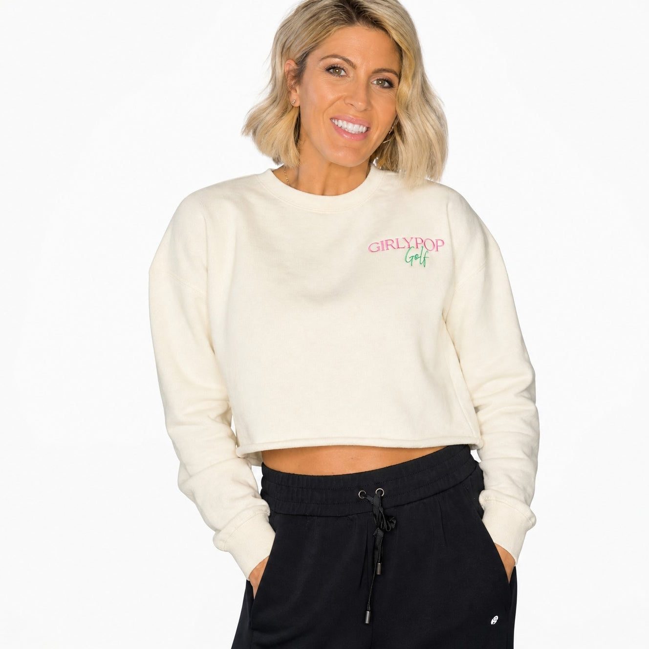 Cream oversized sweatshirt with a small pink and green embroidered logo on the chest.
