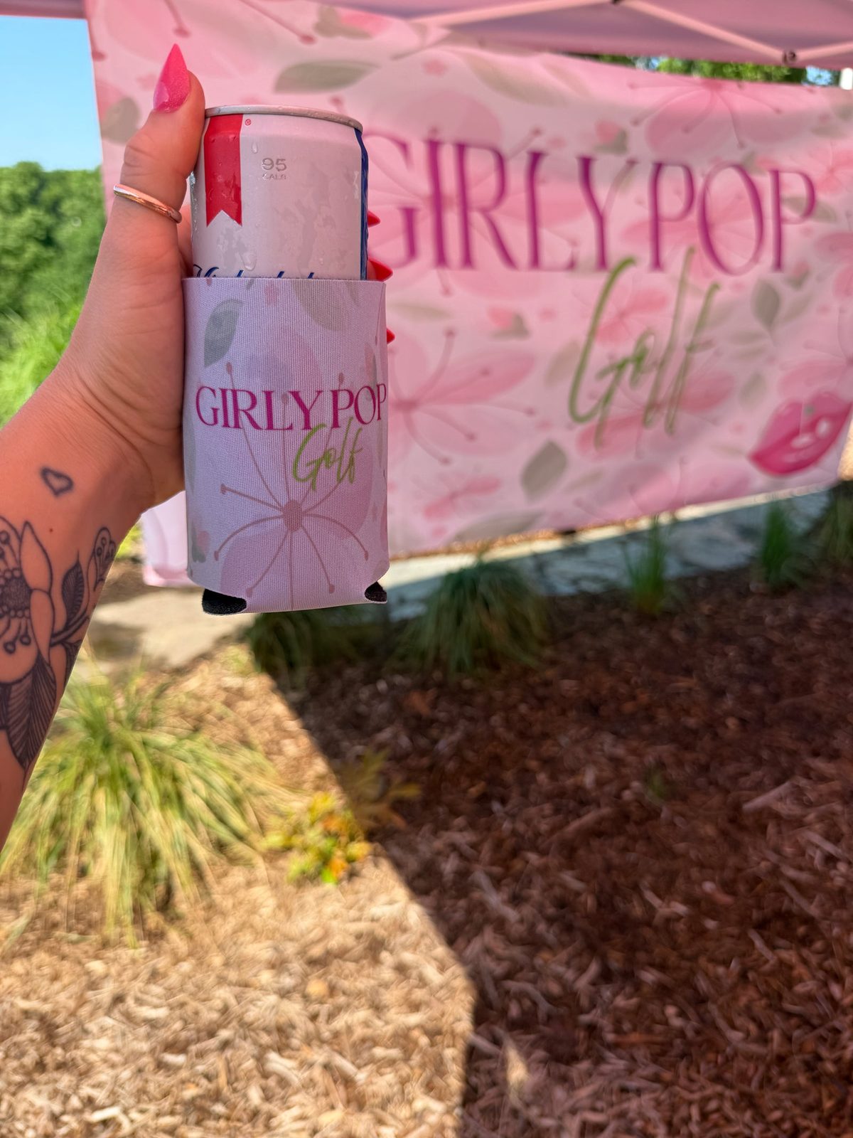 Pink floral koozie with the Girly Pop Golf wordmark.